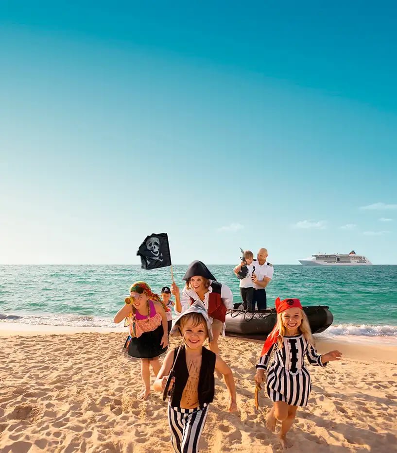 Fünf Kinder sind al Piraten verkleidet und laufen aus einem Schlauchboot am Strand in Richtung Kamera. Sie werden von den Crewmitgliedern betreut.