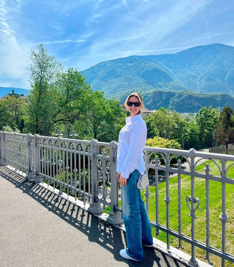 Lorena Burisch im Urlaub, steht an einem Geländer vor einem Bergpanorama