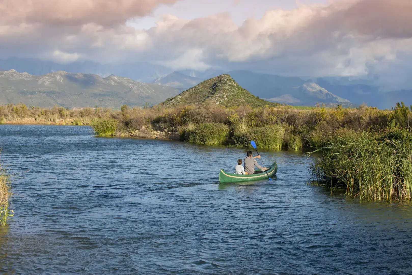 Vater und Sohn fahren in einem Kanu über einen See, im Hintergrund sind Berge.