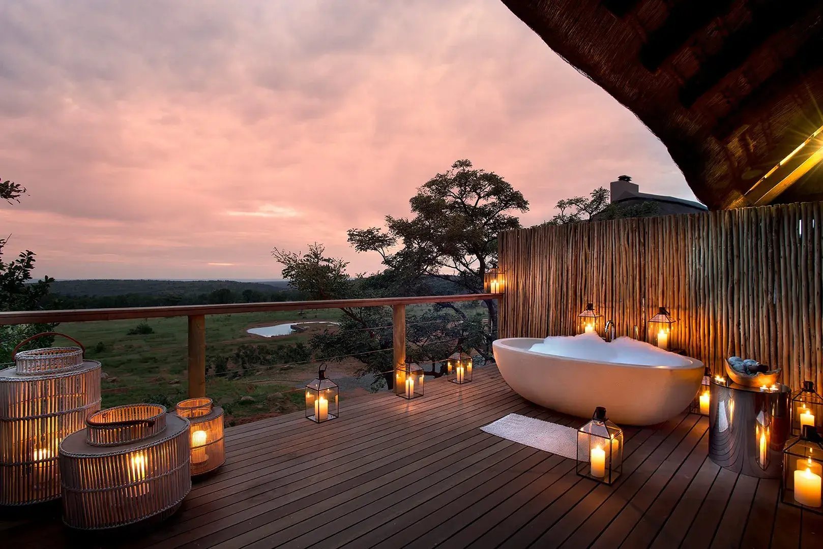 Mit Kerzen beleuchtete Terrasse auf der eine Badewanne steht.