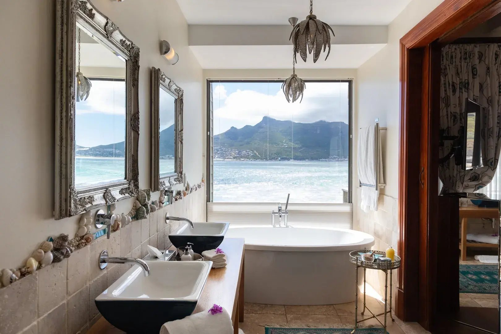 Badezimmer in einem Hotel mit zwei Waschbecken, Badewanne und Blick auf das Meer.