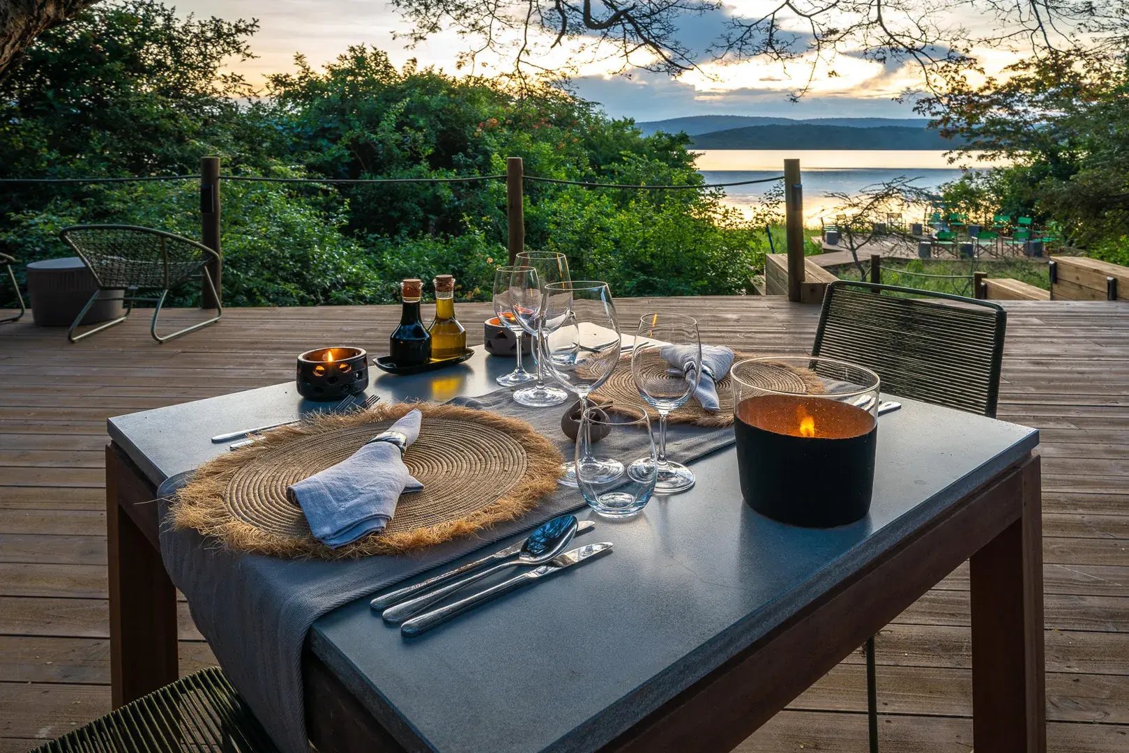 Gedeckter Tisch auf einer Holzterrasse mit Blick in die Natur.