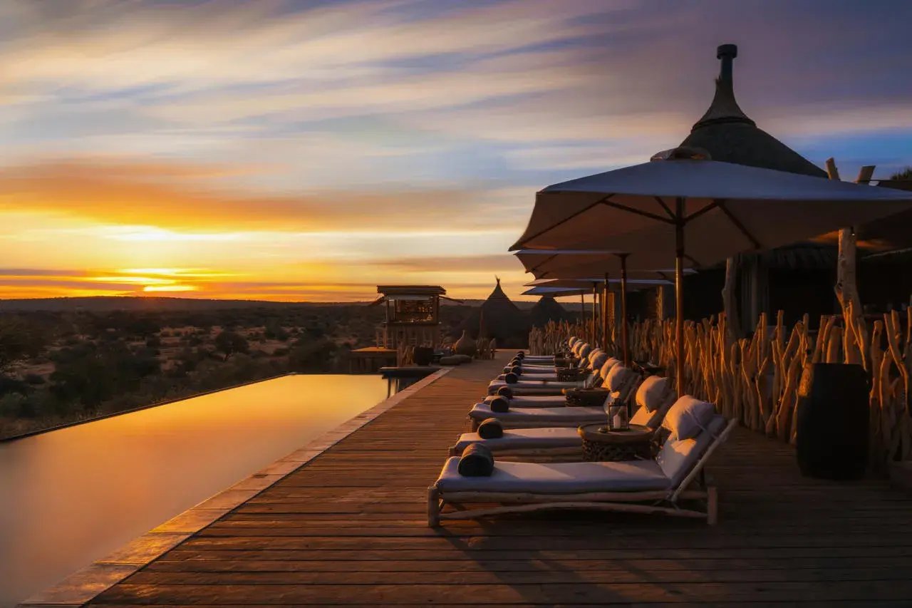 Infinitypool mit Sonnenliegen bei Sonnenuntergang