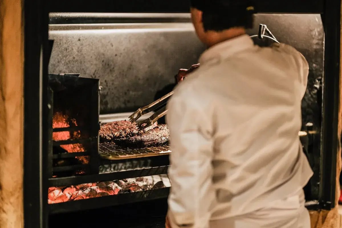 Ein Koch dreht Grillfleisch um.