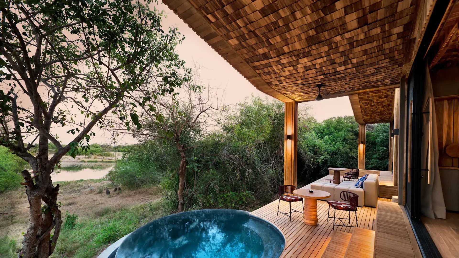 Große Veranda einer Lodge mit Pool, ein Fluss fließt vorbei.