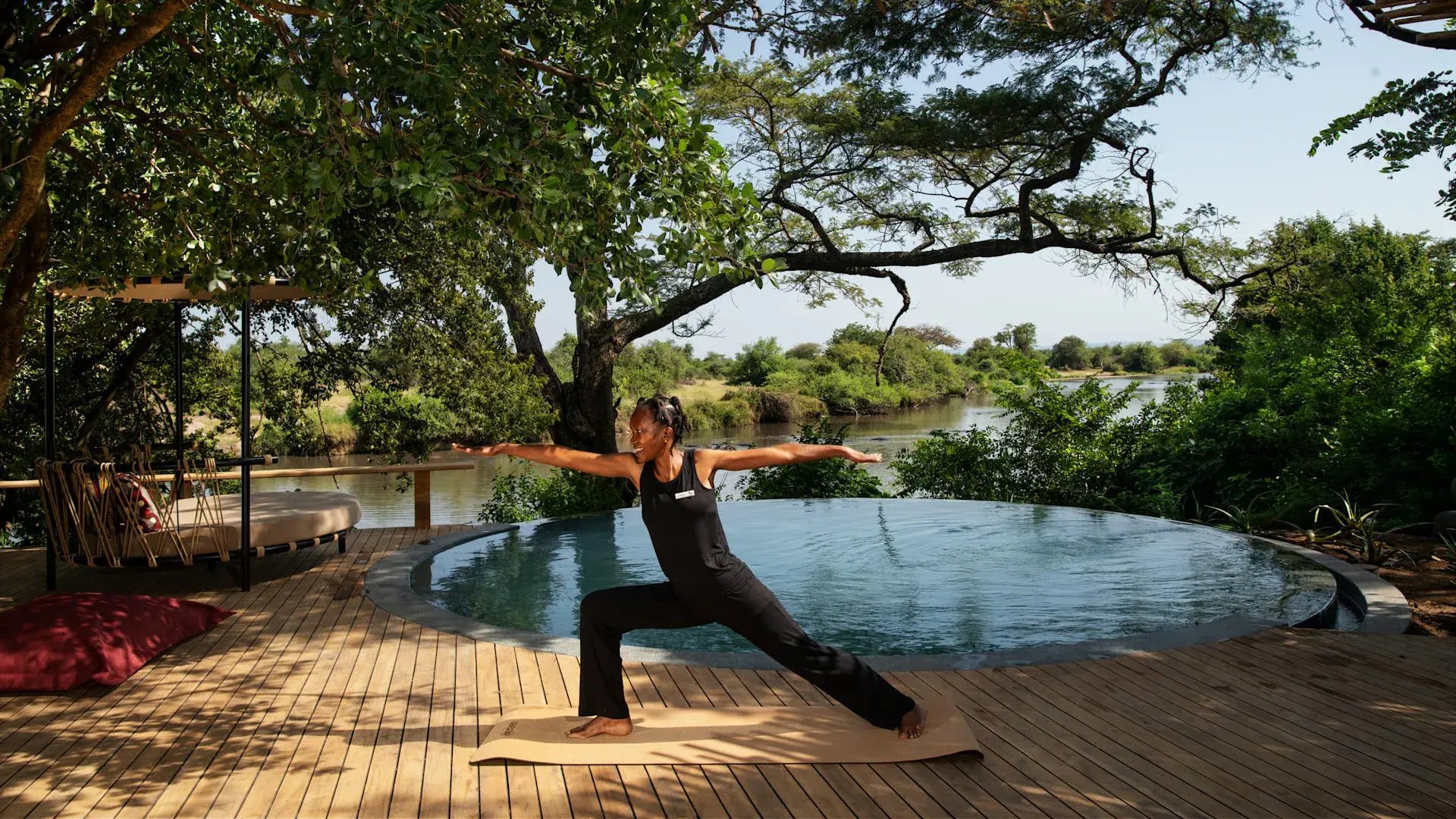 Eine Frau macht Yoga neben einem Pool.