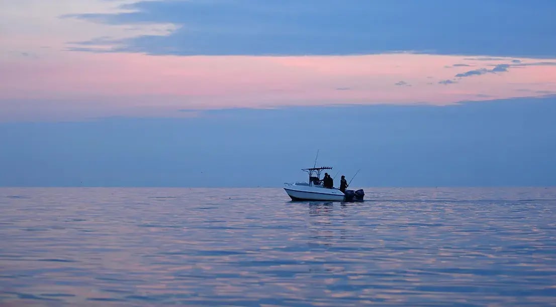 Fischer sind mit einem Boot im Morgengrauen auf dem Meer und Angeln.