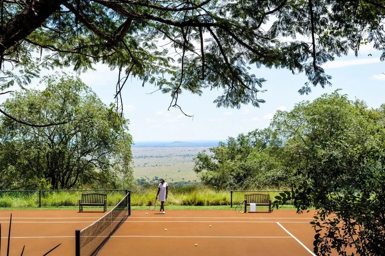 Eine Frau steht am Rande eines Tennisplatzes. 