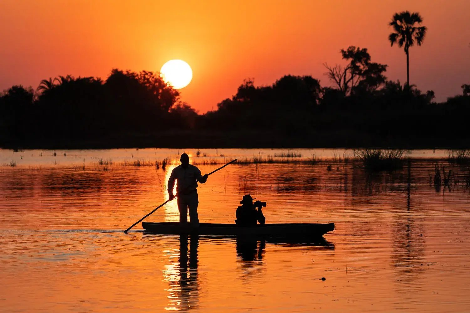 Boot bei Sonnenuntergang, die Umgebung liegt bei rotem Abendlicht im Schatten.